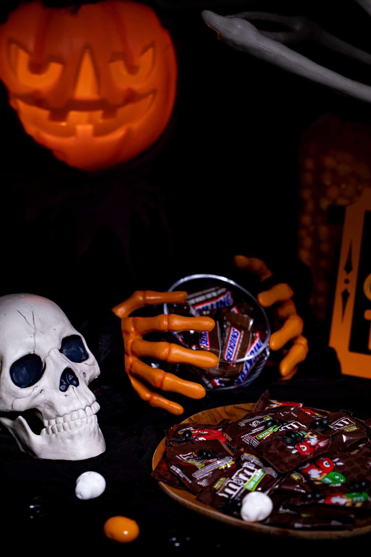 Snickers bars in a bowl held by plastic skeleton hands.