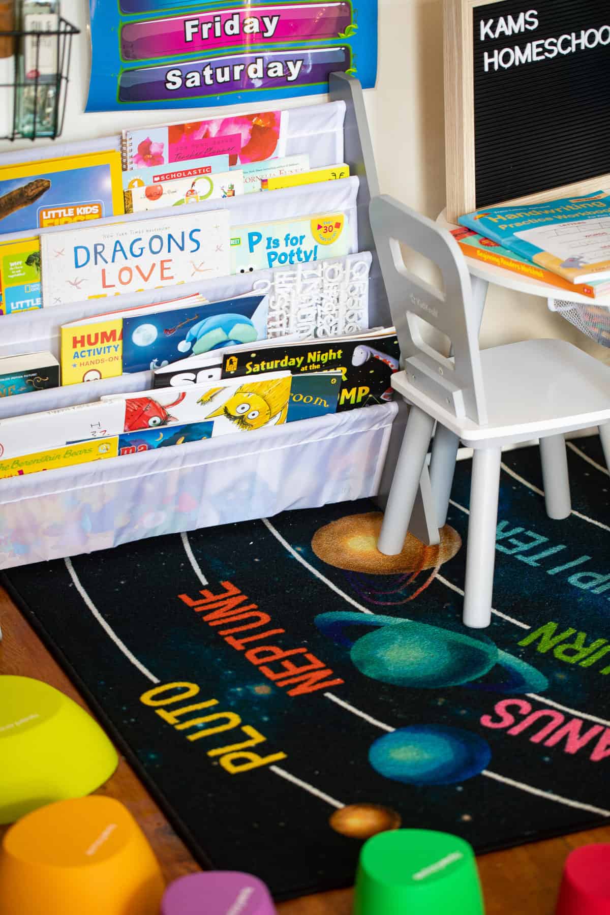 Book shelf full of children\'s books on a rug with the planets.