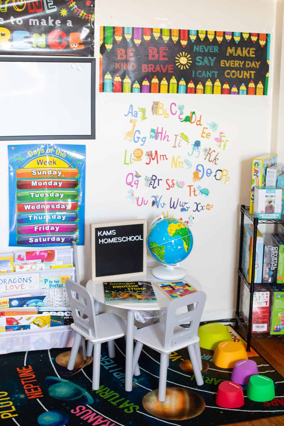 Small table with a sign that says \"Kams Homeschool\" in a room with colorful posters and books.