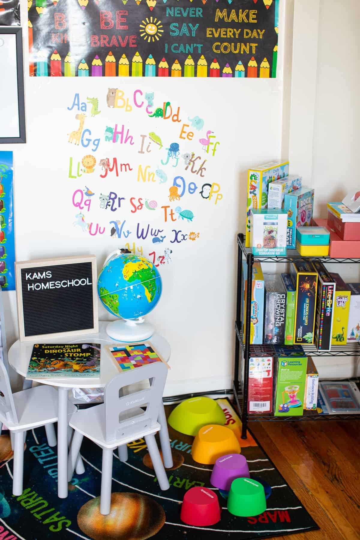 Alphabet on a white wall in a room with science activities, a table, and other educational tools.