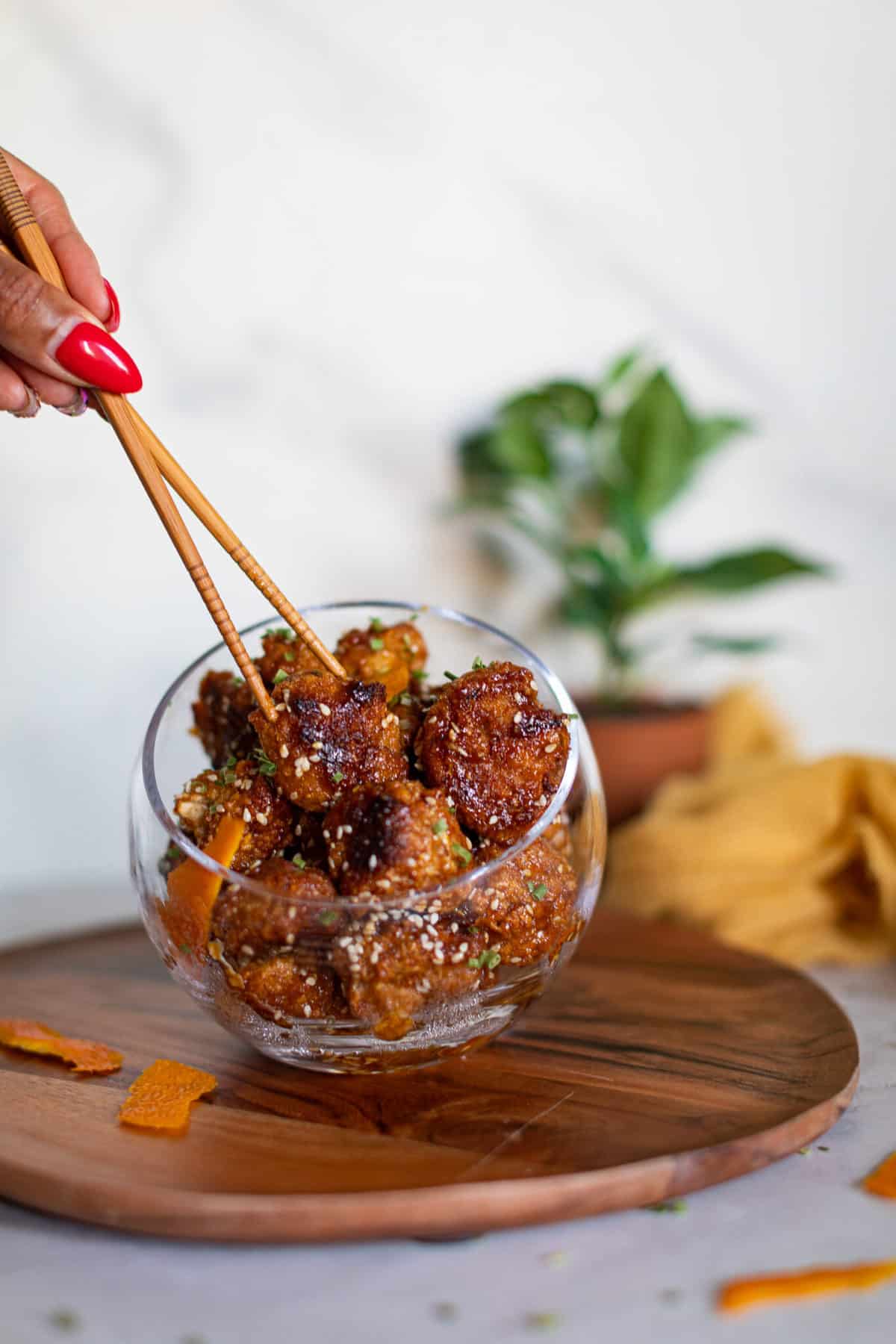 Woman grabbing Crispy Baked Sticky Orange Cauliflower Bites with chopsticks.