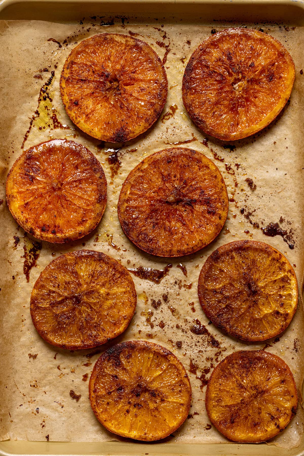 Roasted, seasoned orange slices on a baking sheet