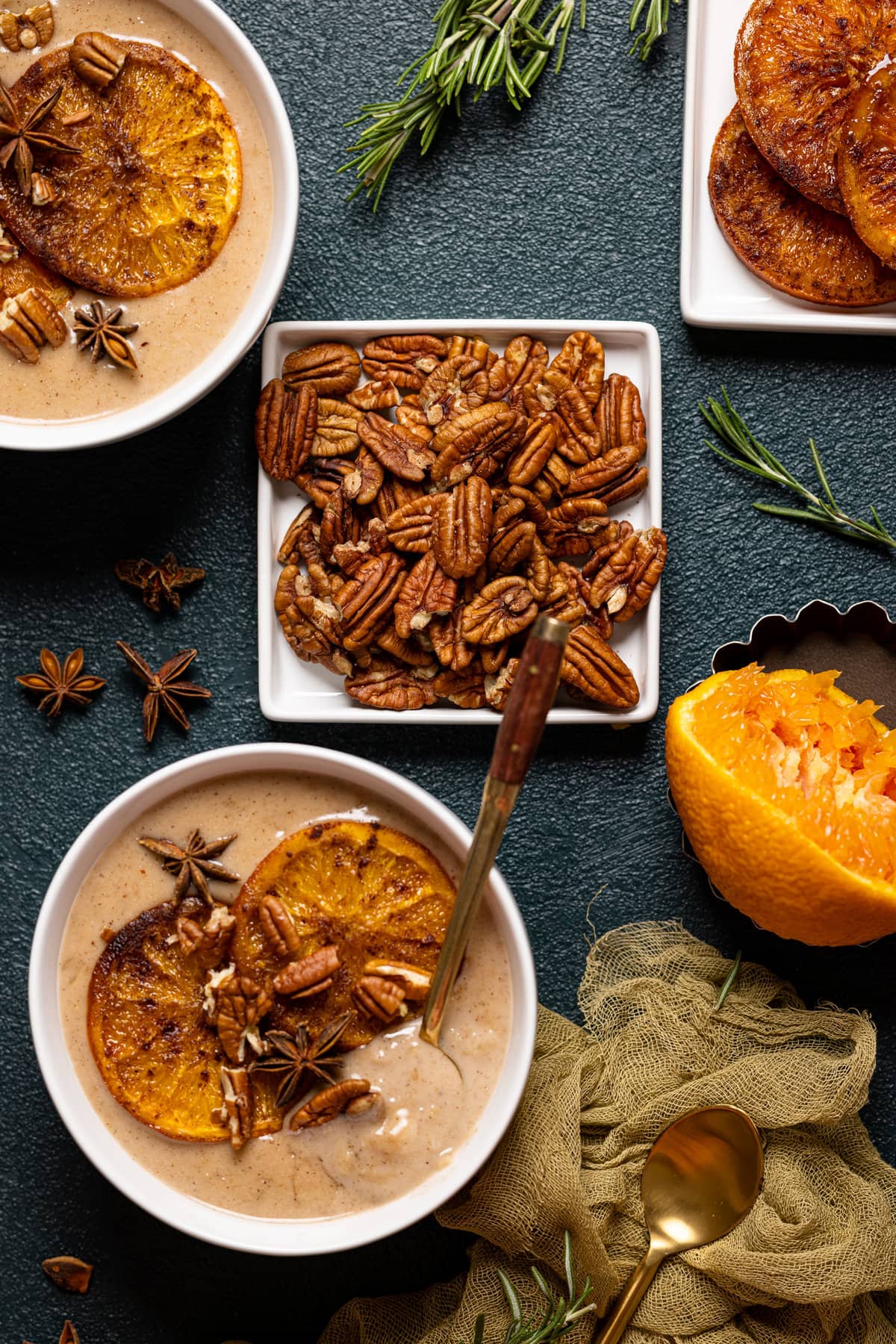 Plate of pecans near bowls of Maple Cinnamon Oatmeal with Roasted Oranges