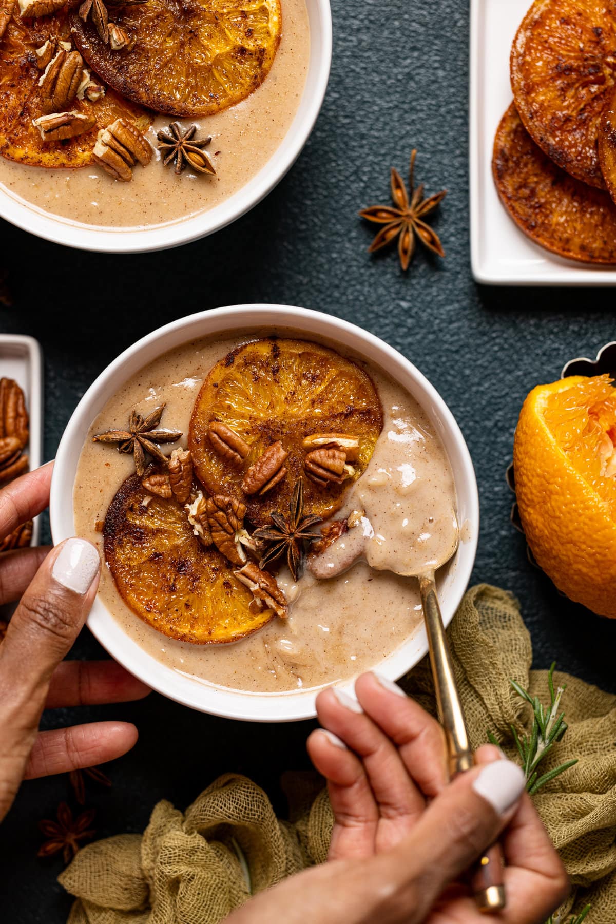 Hands holding a bowl of Maple Cinnamon Oatmeal with Roasted Oranges