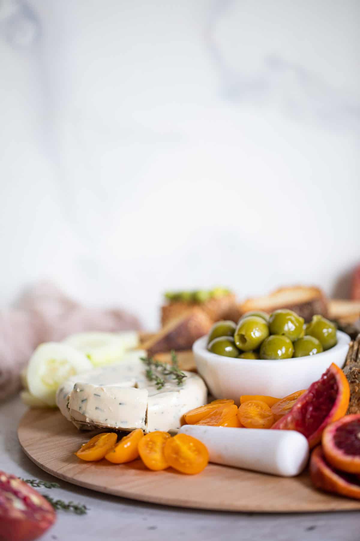 Vegan cheese on a charcuterie board with olives and fruit.