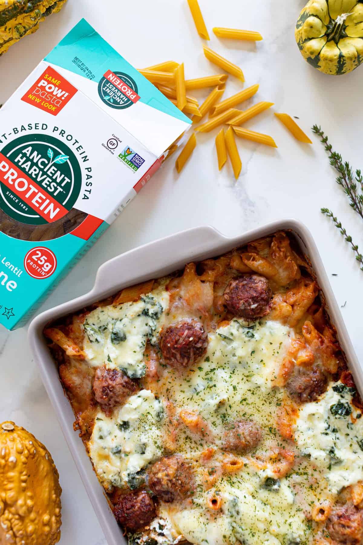 Gluten-free Baked Meatball Penne Pasta Casserole next to a box of Ancient Harvest Protein Pasta.