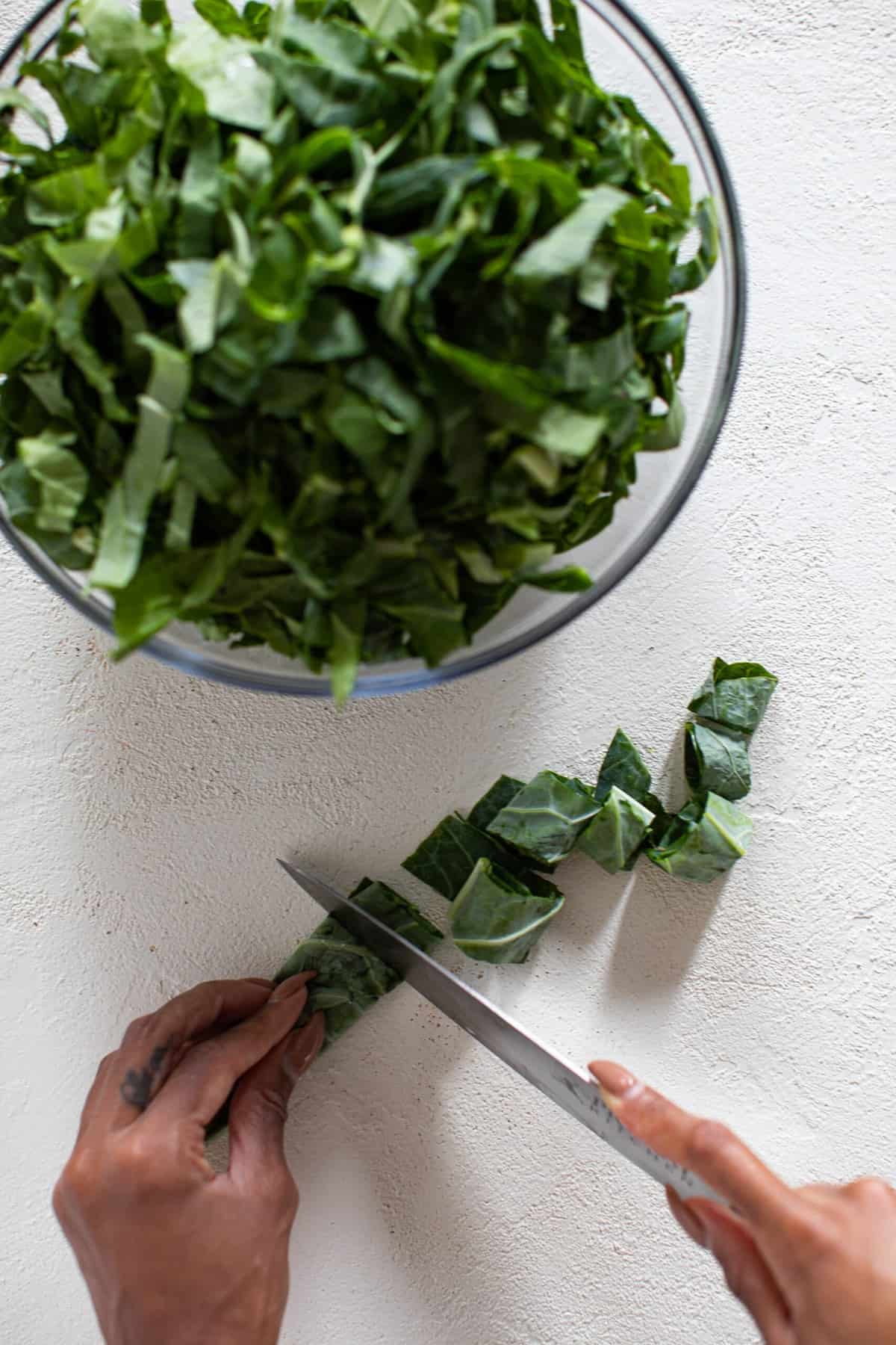 Person chopping rolled-up collard greens