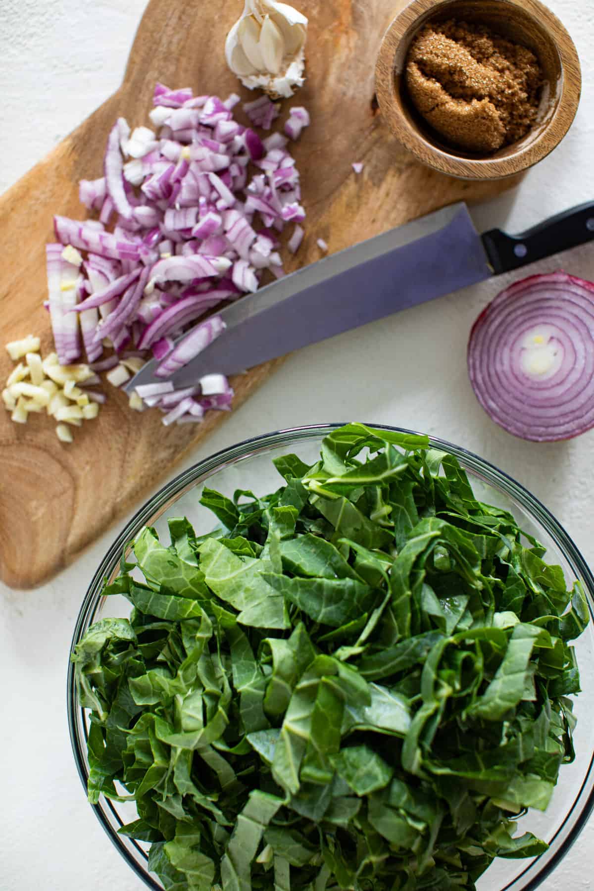 Bowl of sliced collard green next to chopped red onion