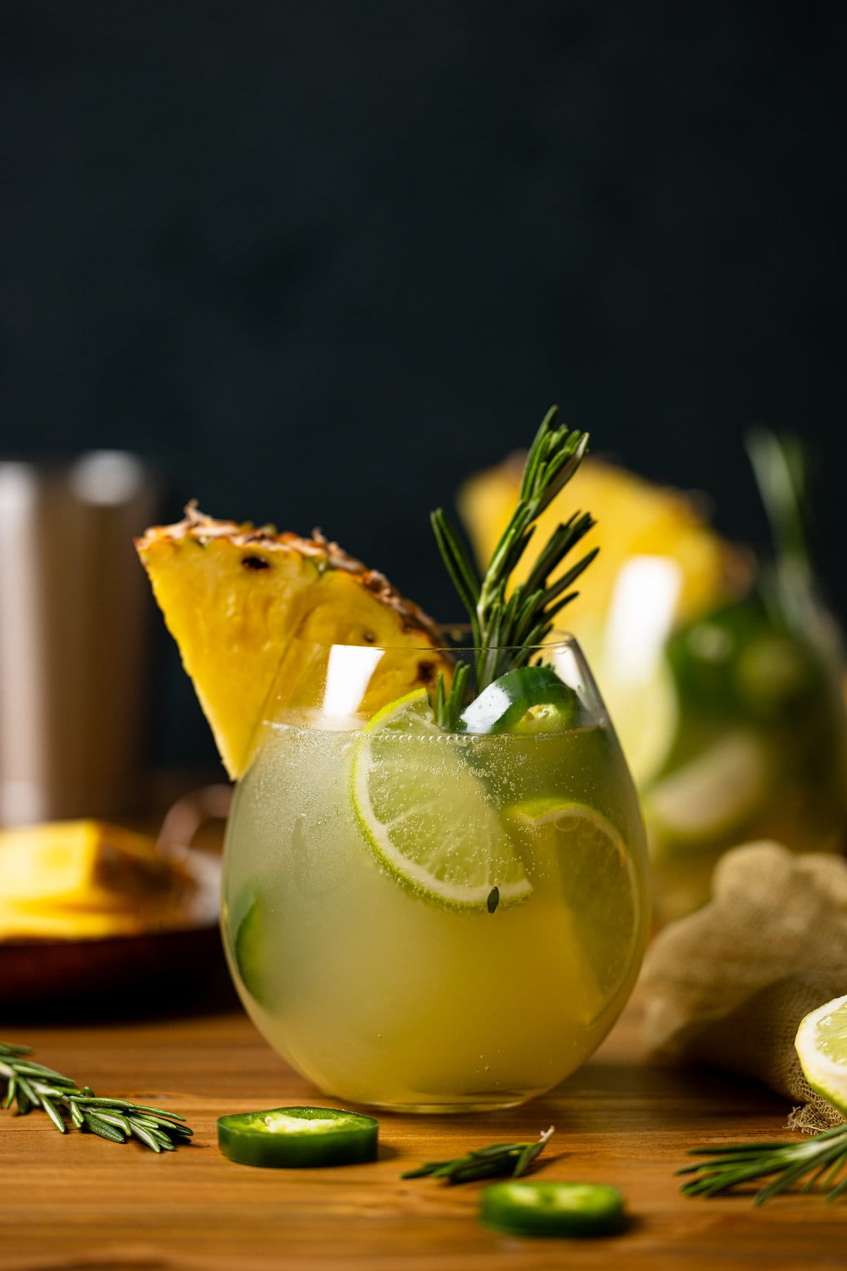 Pineapple Jalapeño Lime Mocktail with lime wedges, a pineapple slice, and a sprig of rosemary