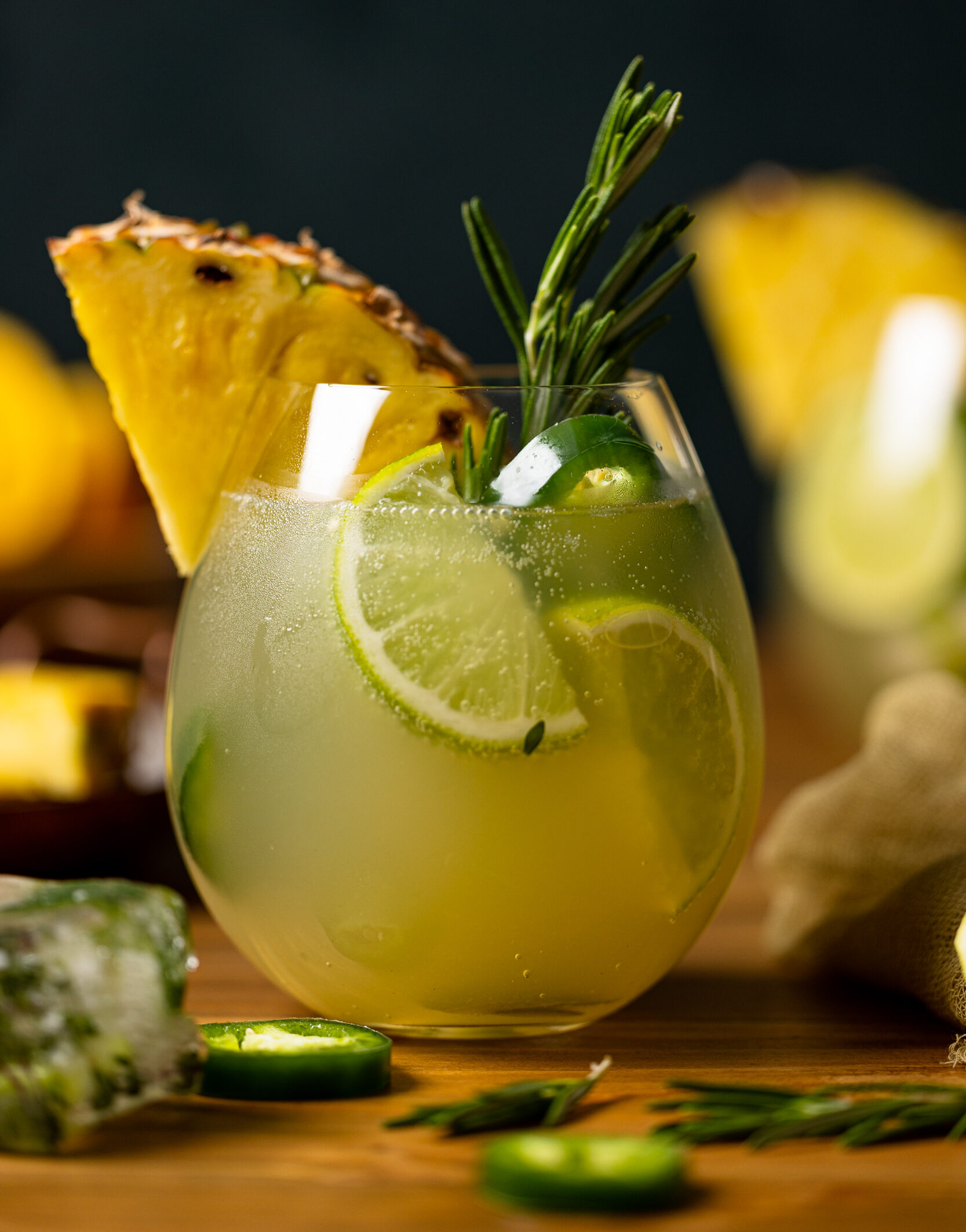 Pineapple Jalapeño Lime Mocktail with lime wedges, a pineapple slice, and a sprig of rosemary