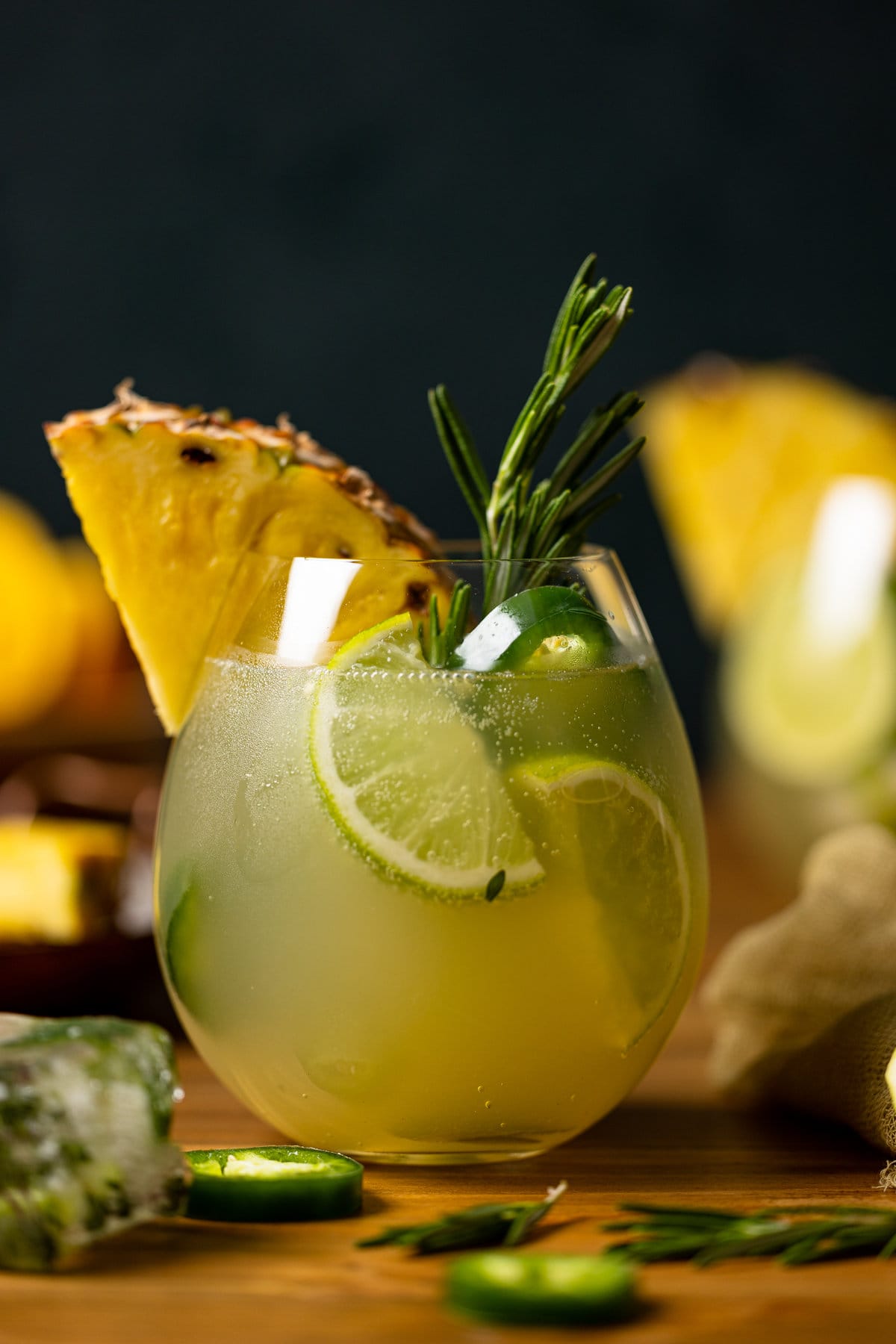 Pineapple Jalapeño Lime Mocktail with lime wedges, a pineapple slice, and a sprig of rosemary