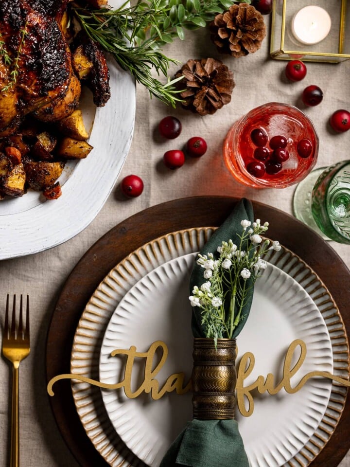 Beautifully set table with a plate decoration that reads "thankful" and various fall adornements