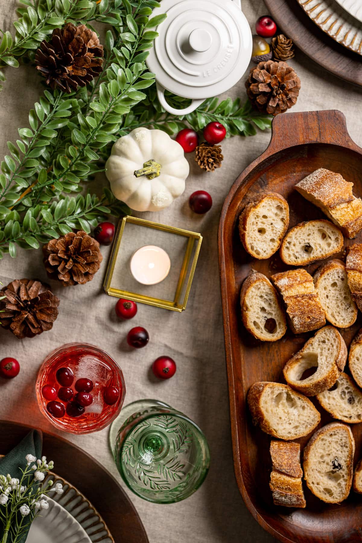 Overhead shot of a table setting with pinecones, greenery, bread, and other fall decorations