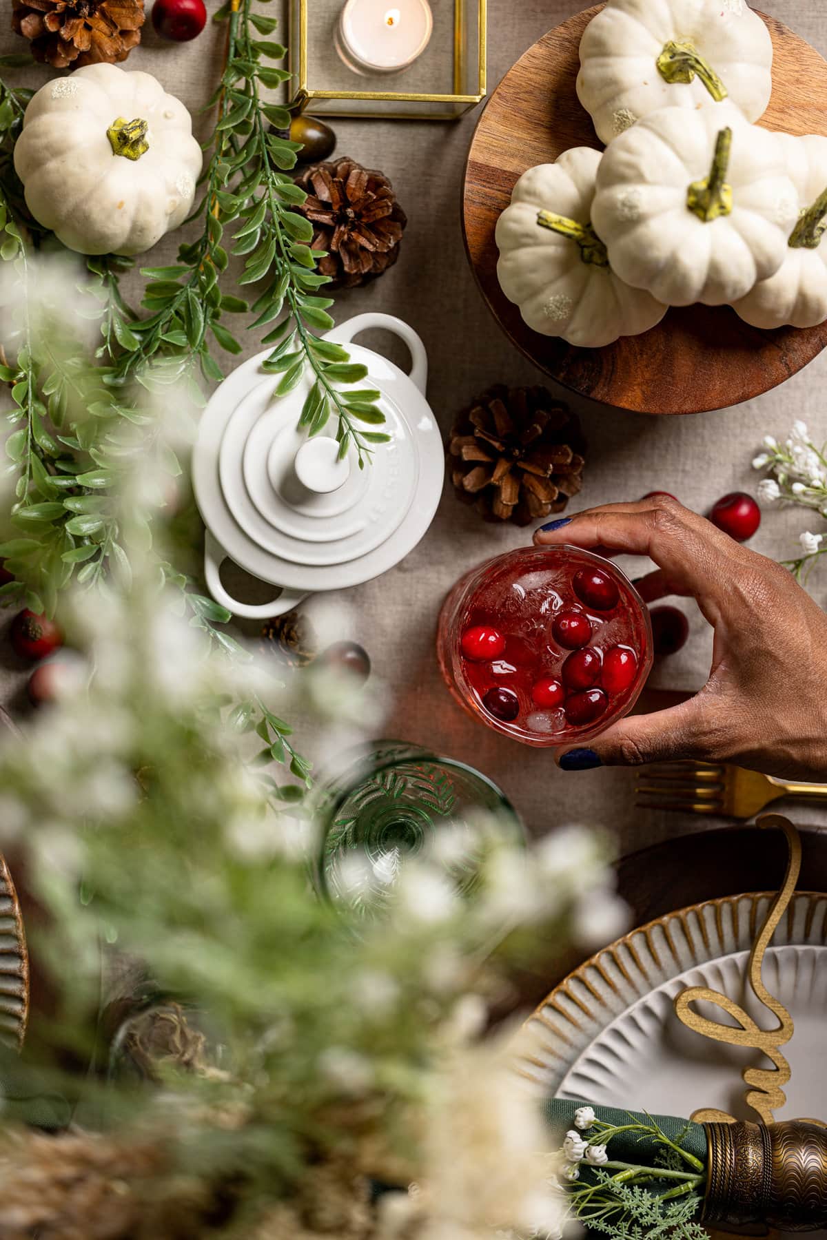 Hand grabbing a glass from a table set with fall decorations