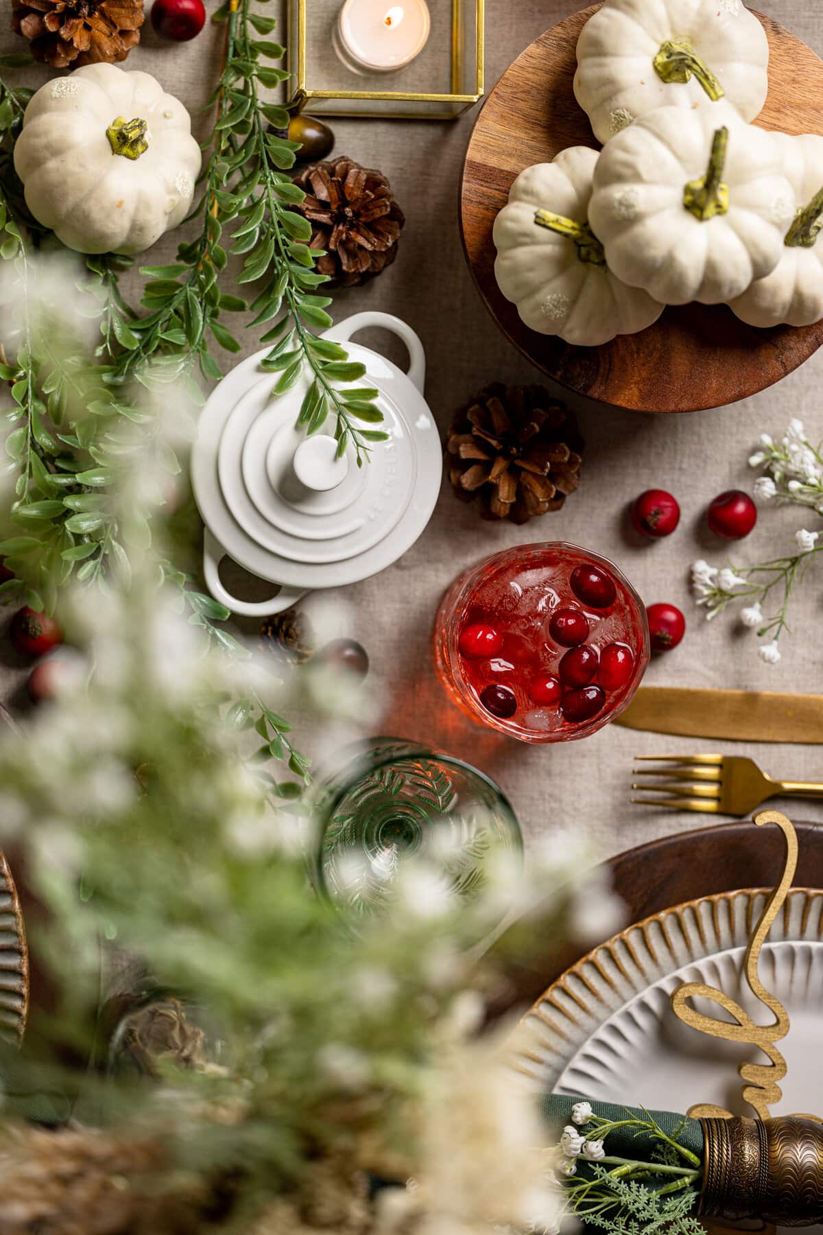 Overhead shot of a table setting with fall decorations including white pumpkins and brown pinecones