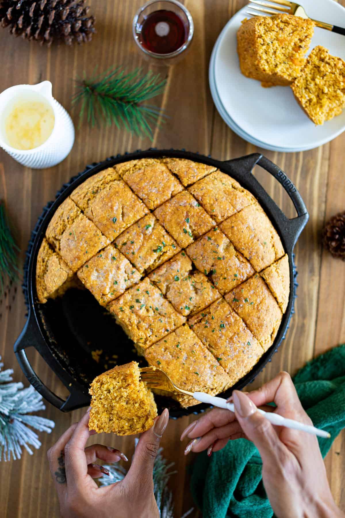 Woman removing a piece of Vegan Sweet Potato Maple Herb Cornbread from a skillet.