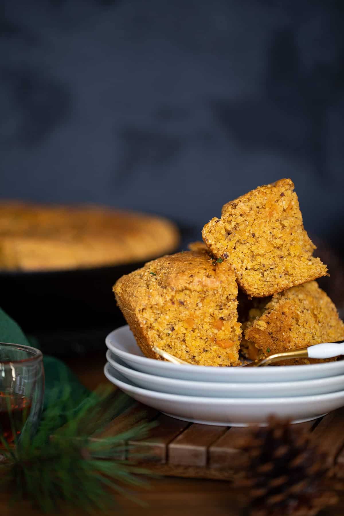 Pieces of Vegan Sweet Potato Maple Herb Cornbread on three small, stacked plates