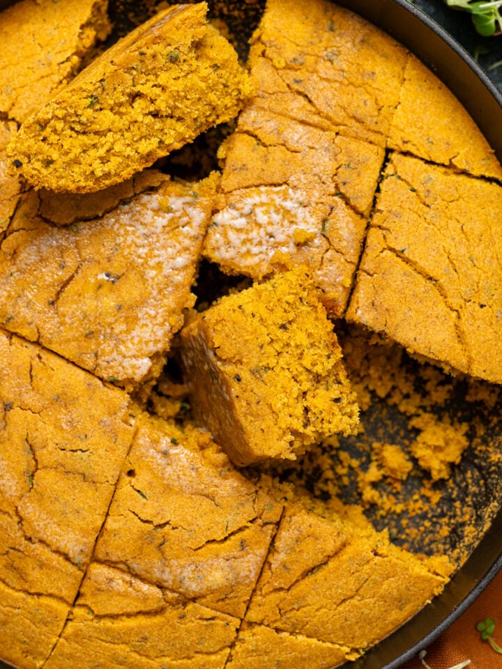 Up close shot of Vegan Sweet Potato Maple Herb Cornbread sliced in a skillet.