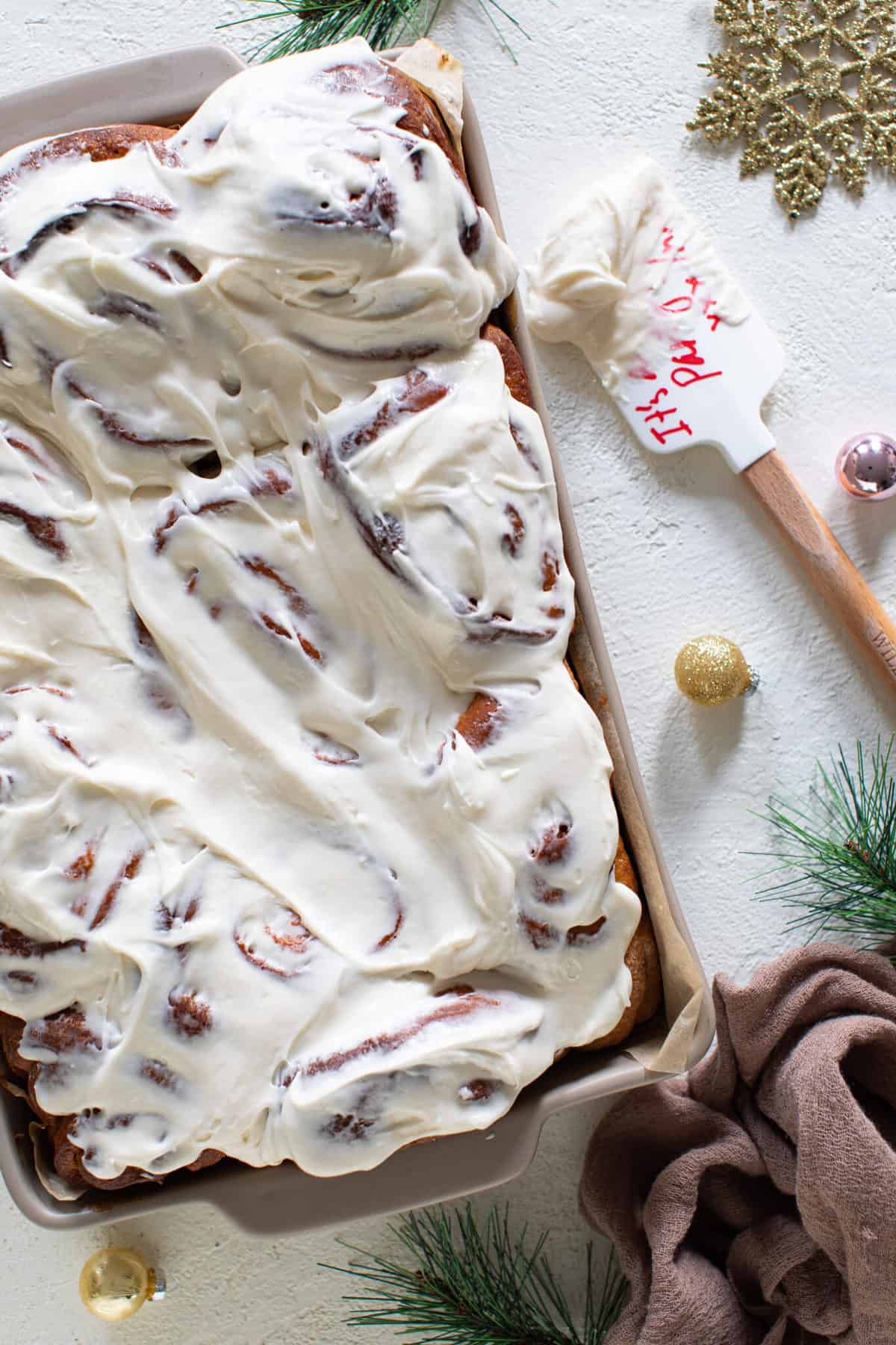 Iced Apple Butter Eggnog Cinnamon Rolls with a spatula of icing.