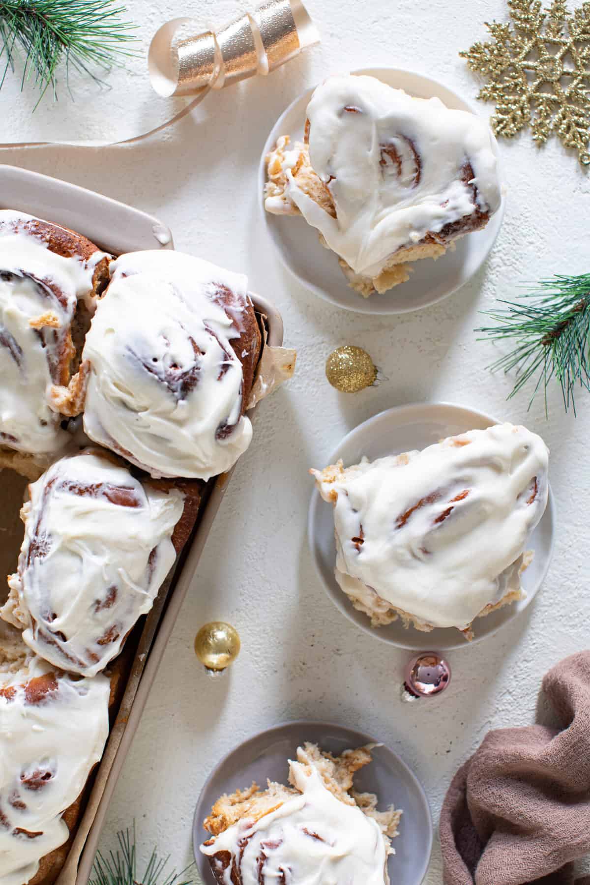 Fluffy Apple Butter Eggnog Cinnamon Rolls on plates and in a baking dish.