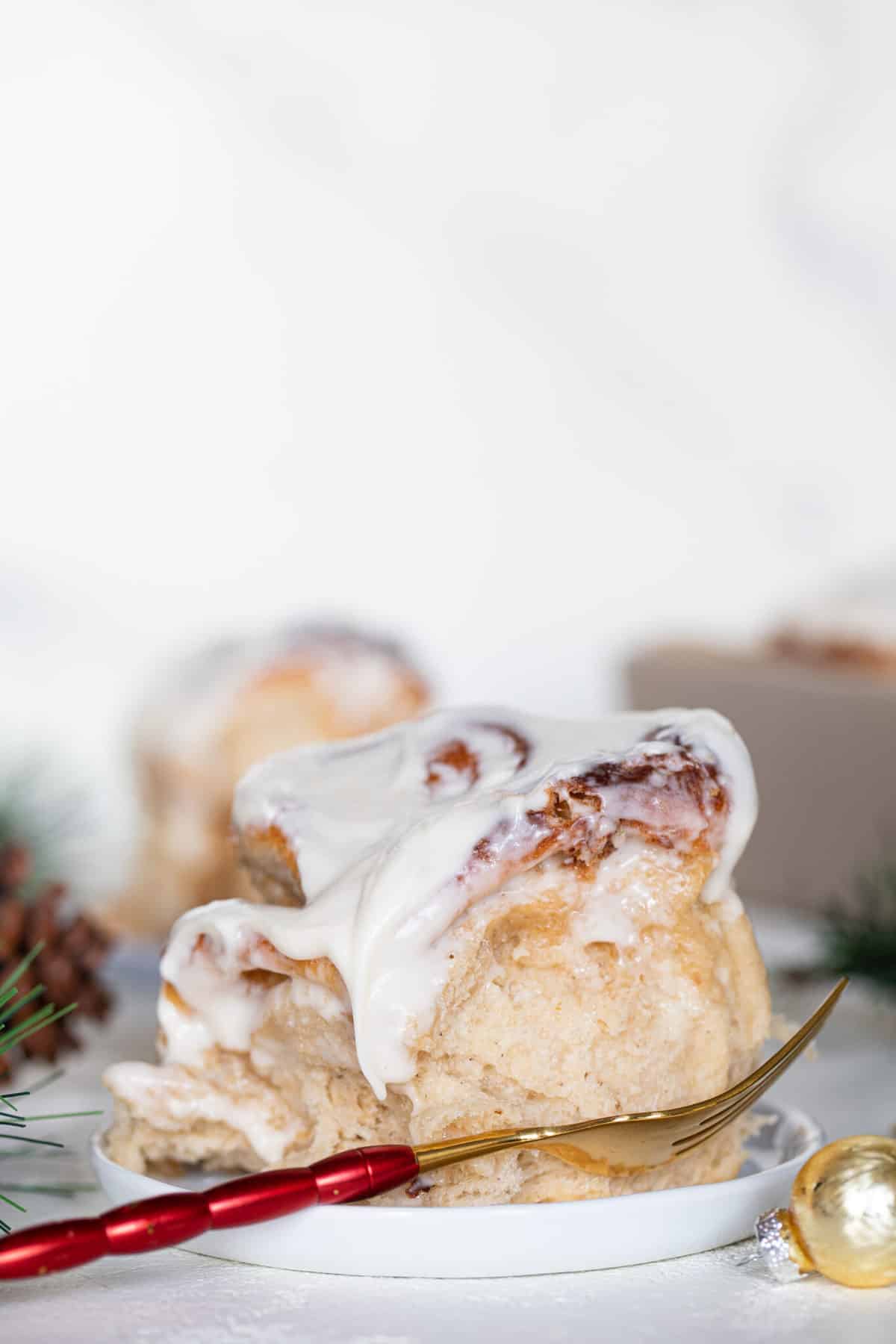 Fluffy Apple Butter Eggnog Cinnamon Rolls on a small plate with a fork.