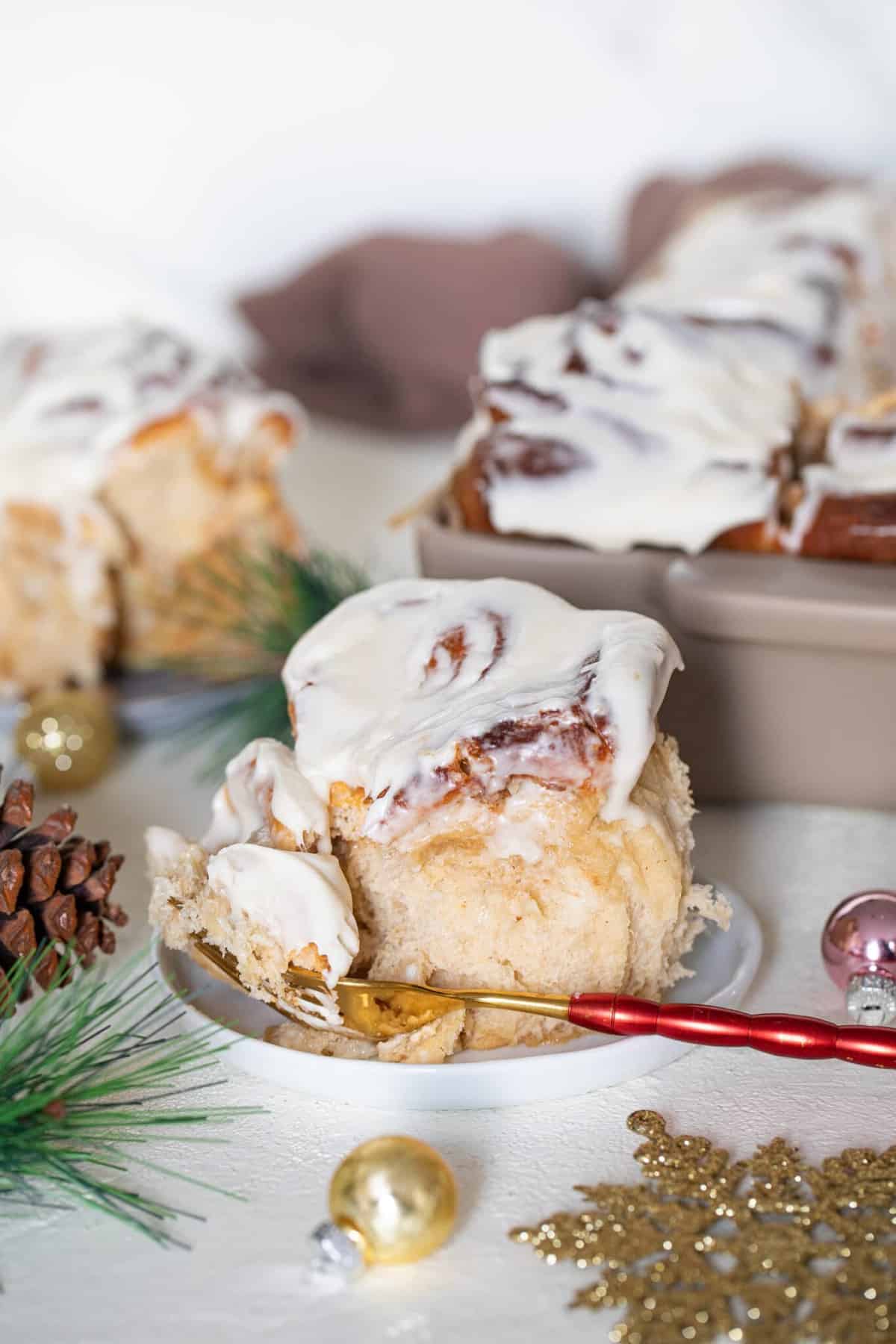 Red fork on a plate with a Fluffy Apple Butter Eggnog Cinnamon Roll.