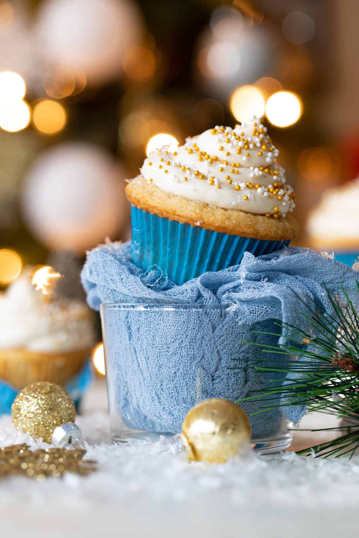 Eggnog Cupcake with Cream Cheese Frosting on a blue cloth stuffed in a glass bowl.