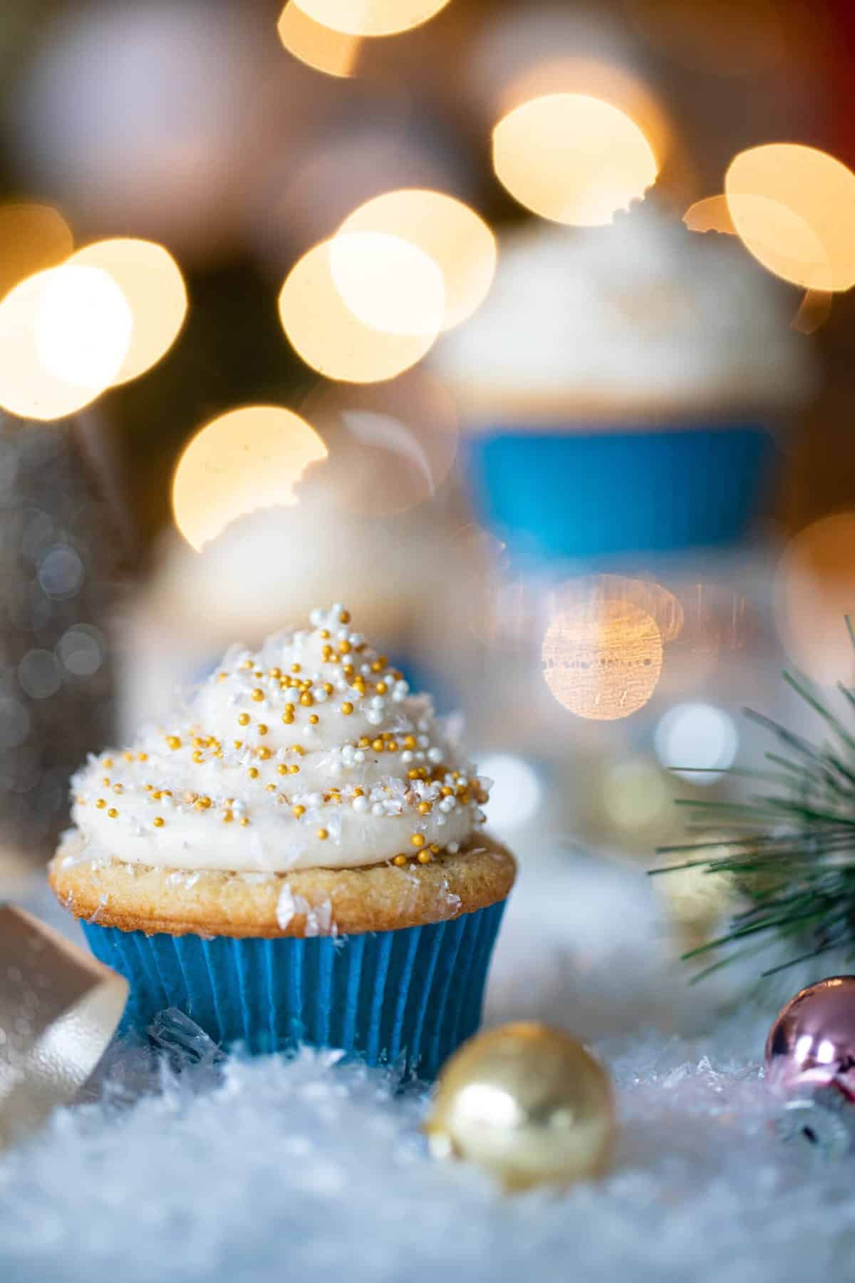 Eggnog Cupcake with Cream Cheese Frosting surrounded by winter decorations.