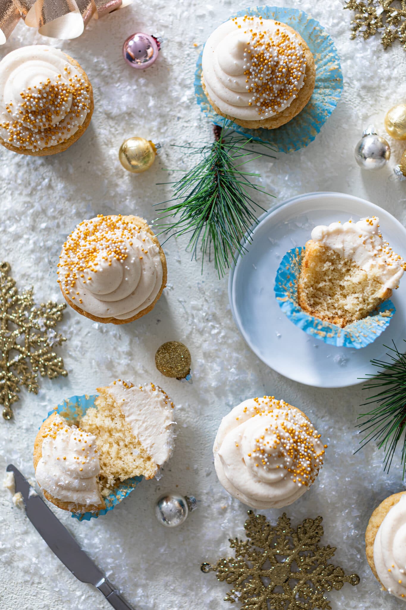 Eggnog Cupcakes with Cream Cheese Frosting on a table of winter decorations.