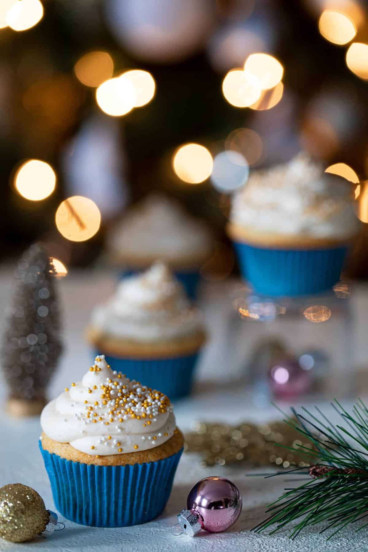 Eggnog Cupcakes with Cream Cheese Frosting on a table with Christmas decorations.