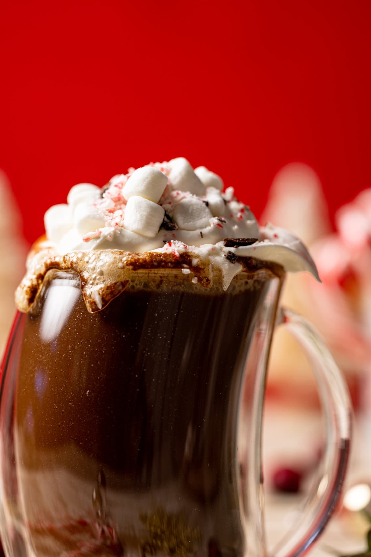 Closeup of a Homemade Peppermint Mocha Latte in a lopsided glass topped with whipped cream and marshmallows