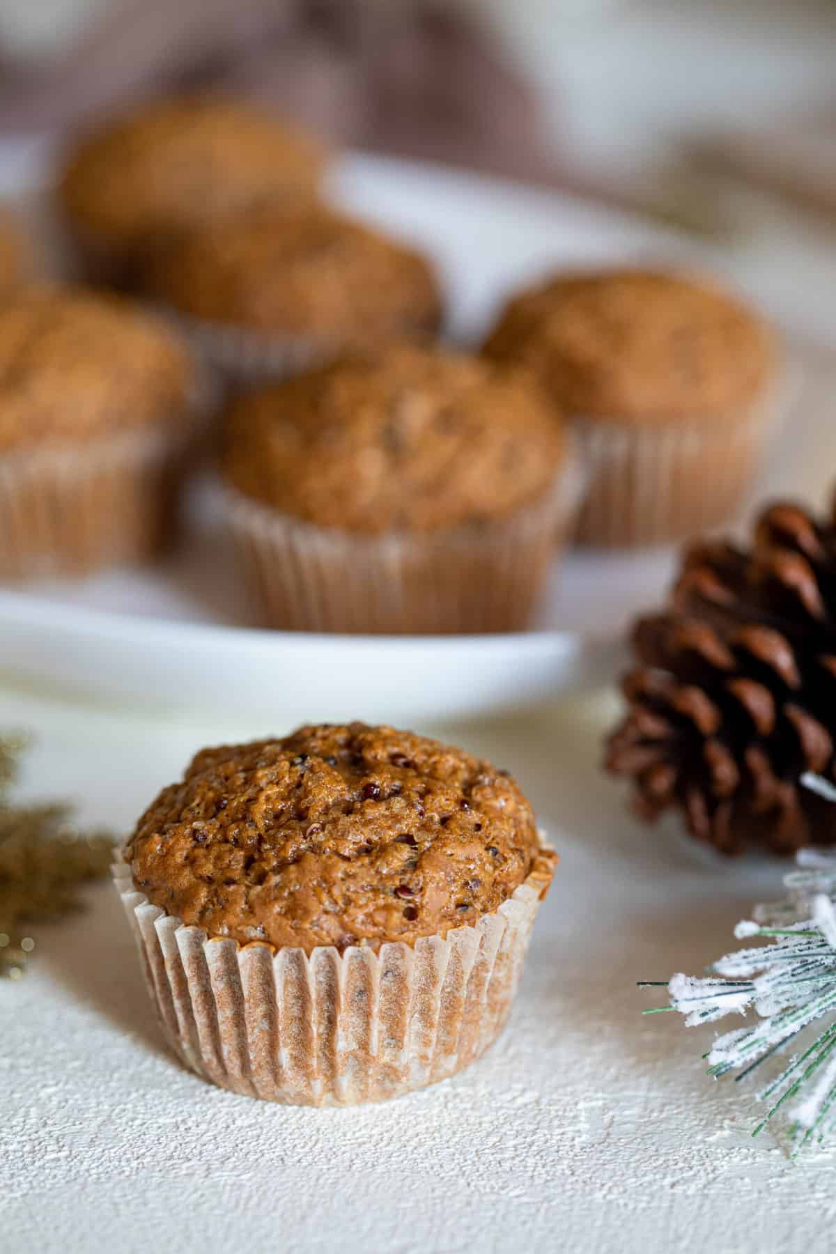 Vegan Gingerbread Quinoa Muffin on a table with a pine cone and other decorations.