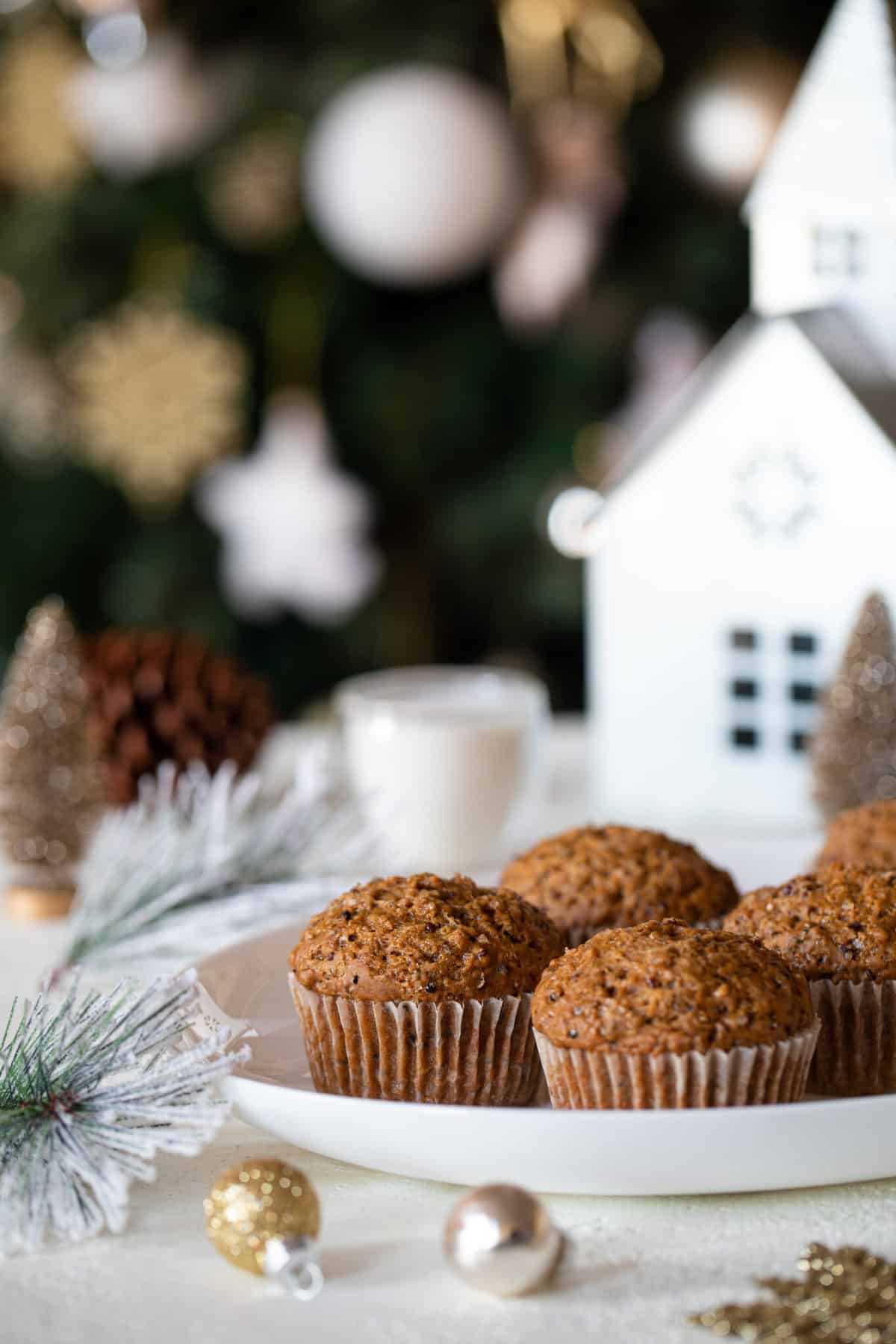 Plate of Vegan Gingerbread Quinoa Muffins surrounded by Christmas decorations.