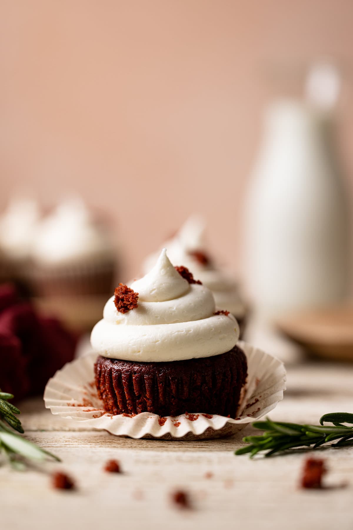 Muffin liner being removed from a Vegan Red Velvet Cupcake with Bourbon Vanilla Buttercream.