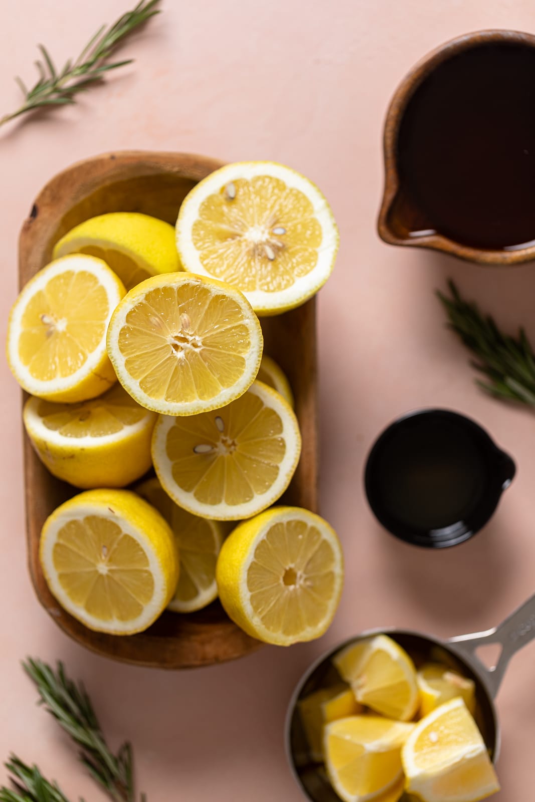 Wooden bowl of lemon halves near honey and rosemary