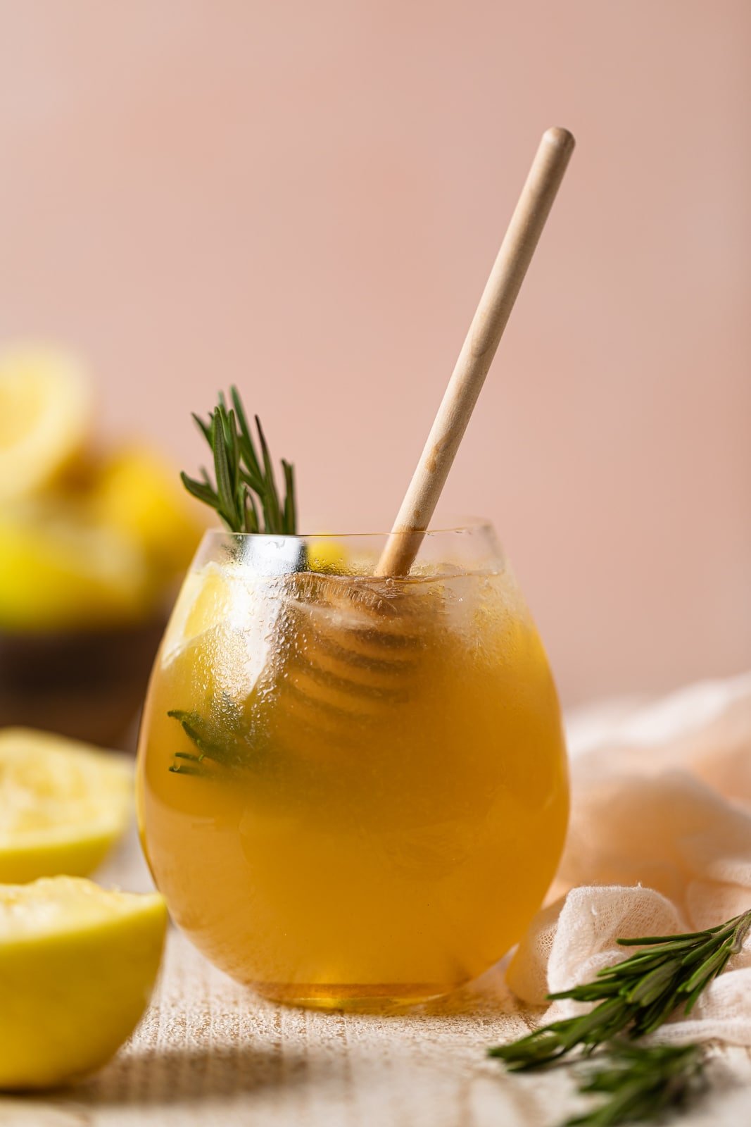 Glass of Apple Cider Vinegar Detox Lemonade with rosemary sprigs and a honey dipper