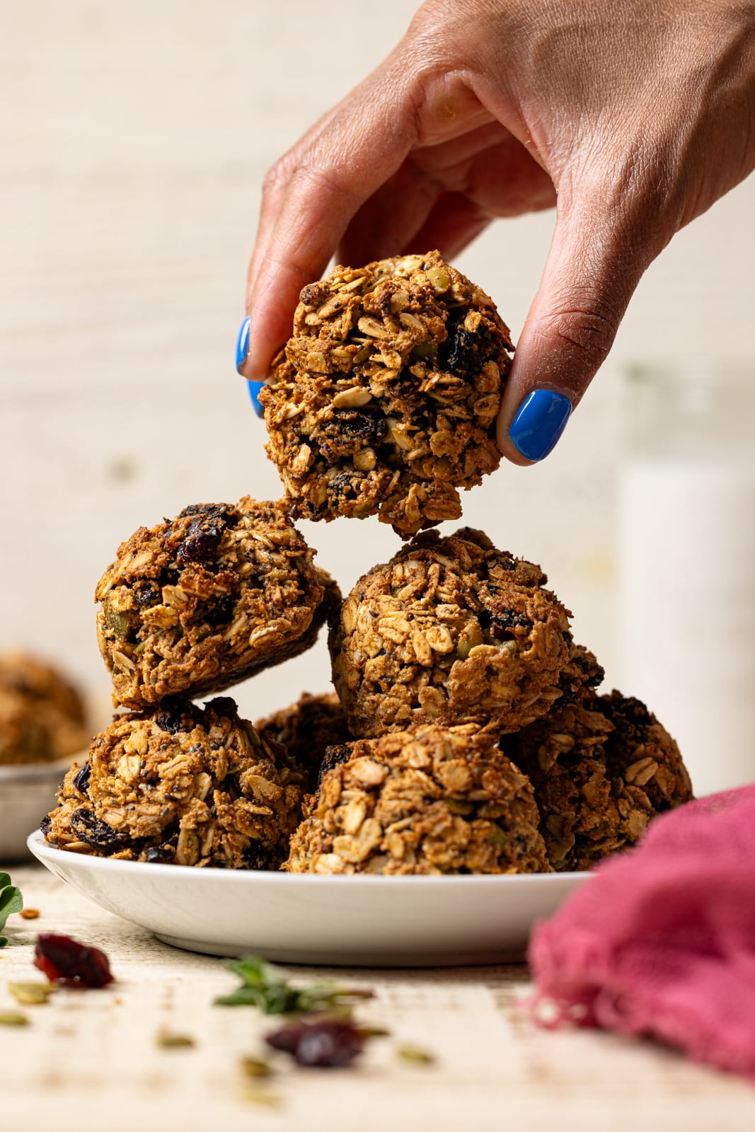 Cookies stacked on a white plate being held by hand.