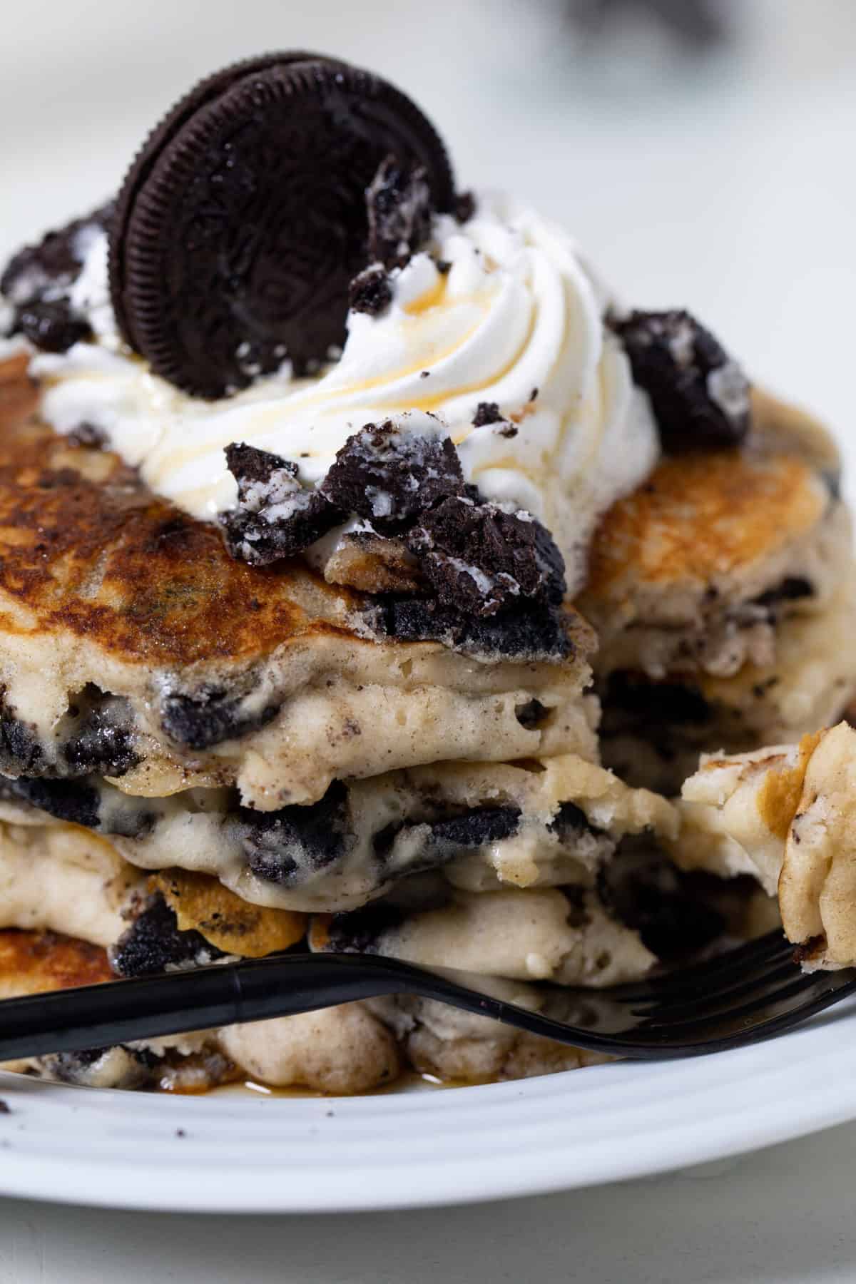 Fluffy Vegan Oreo Pancakes topped with whipped cream and an Oreo.