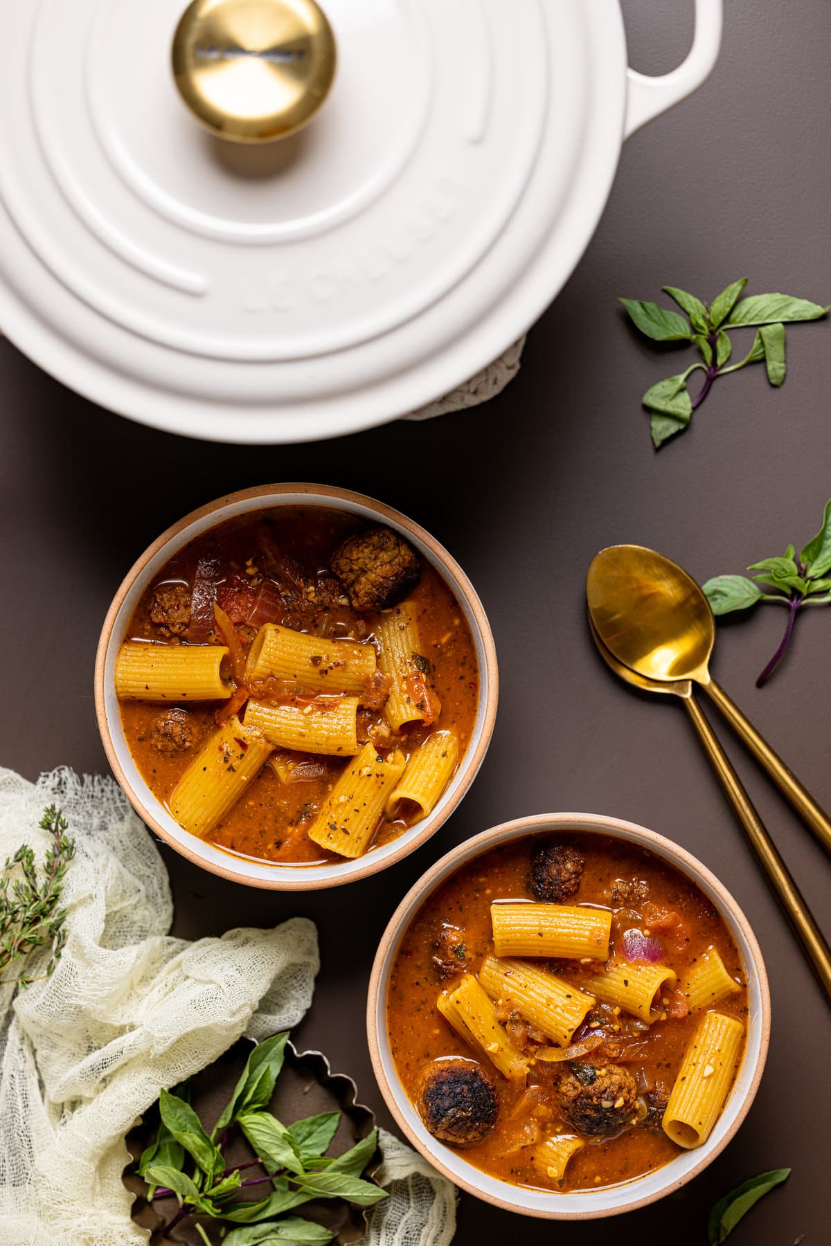 Overhead shot of two bowls of Rigatoni Meatball Soup with spoons