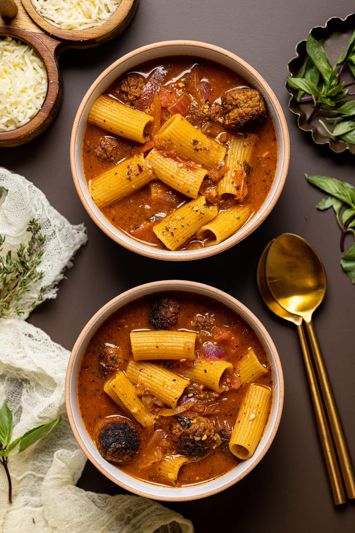 Overhead shot of two bowls of Rigatoni Meatball Soup with spoons