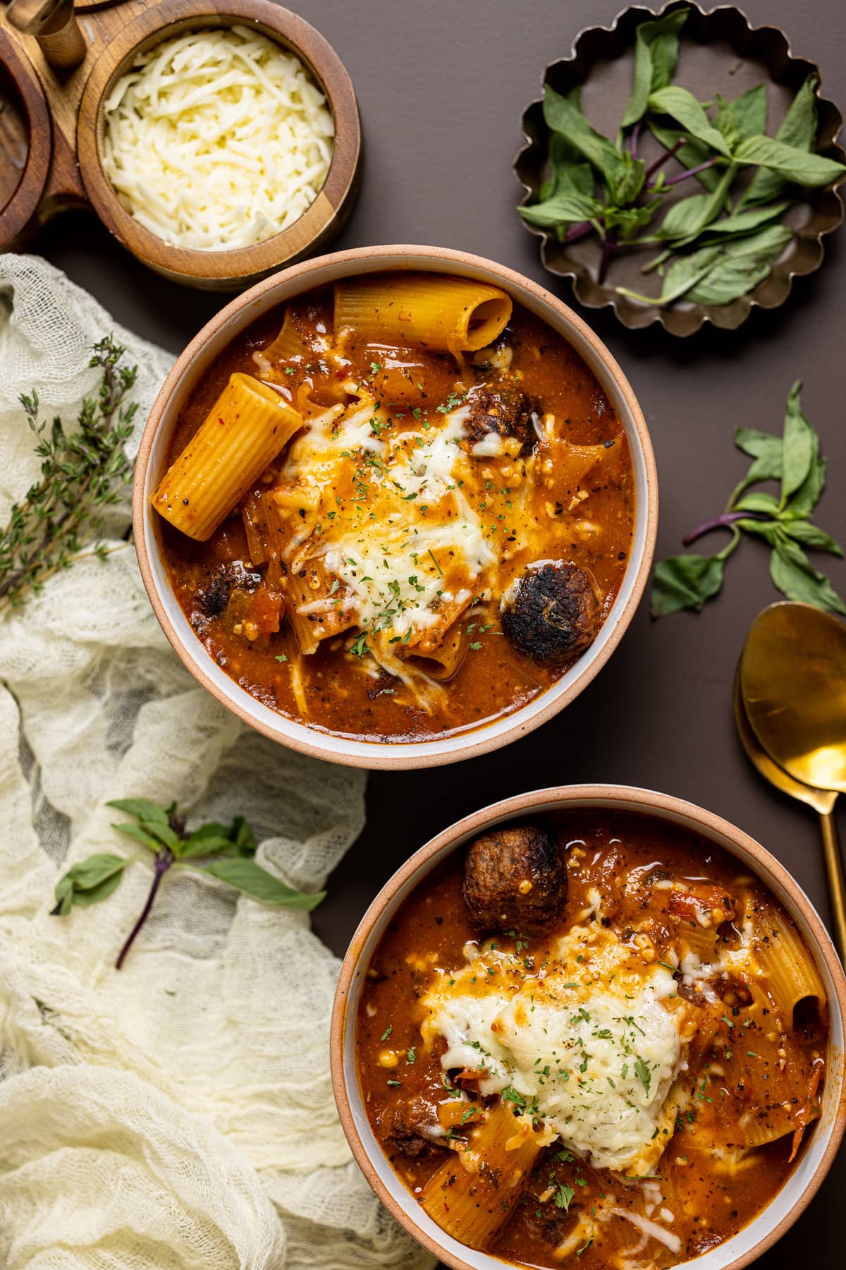 Overhead shot of two bowls of Rigatoni Meatball Soup topped with cheese