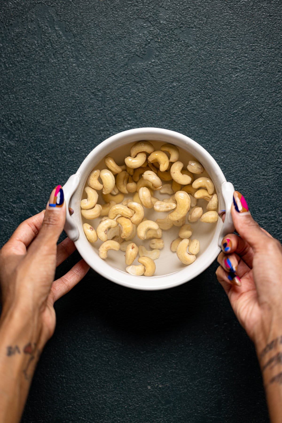 Hands holding a bowl with peanuts soaking in water