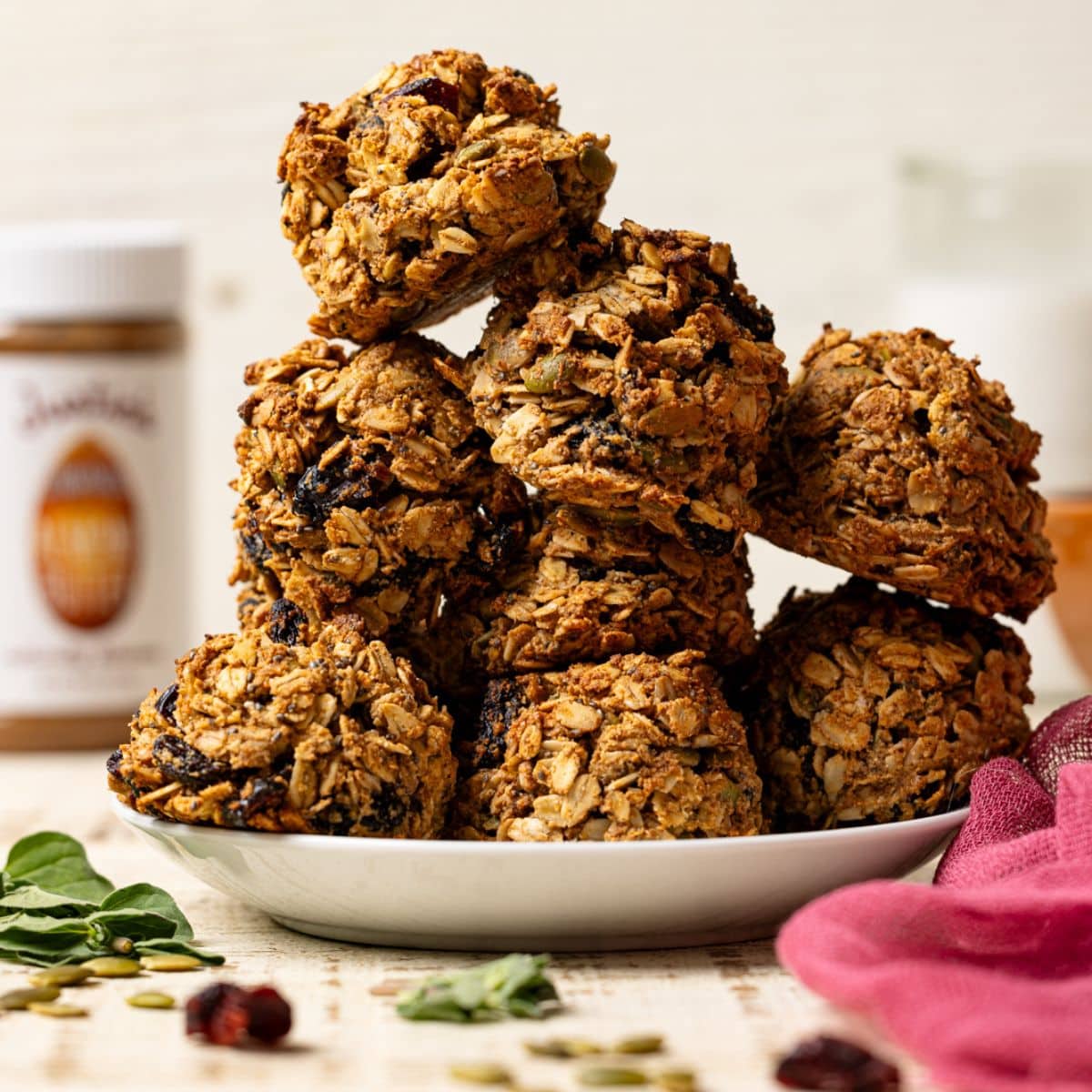 Cookies stacked on a white plate with almond butter and milk in background.