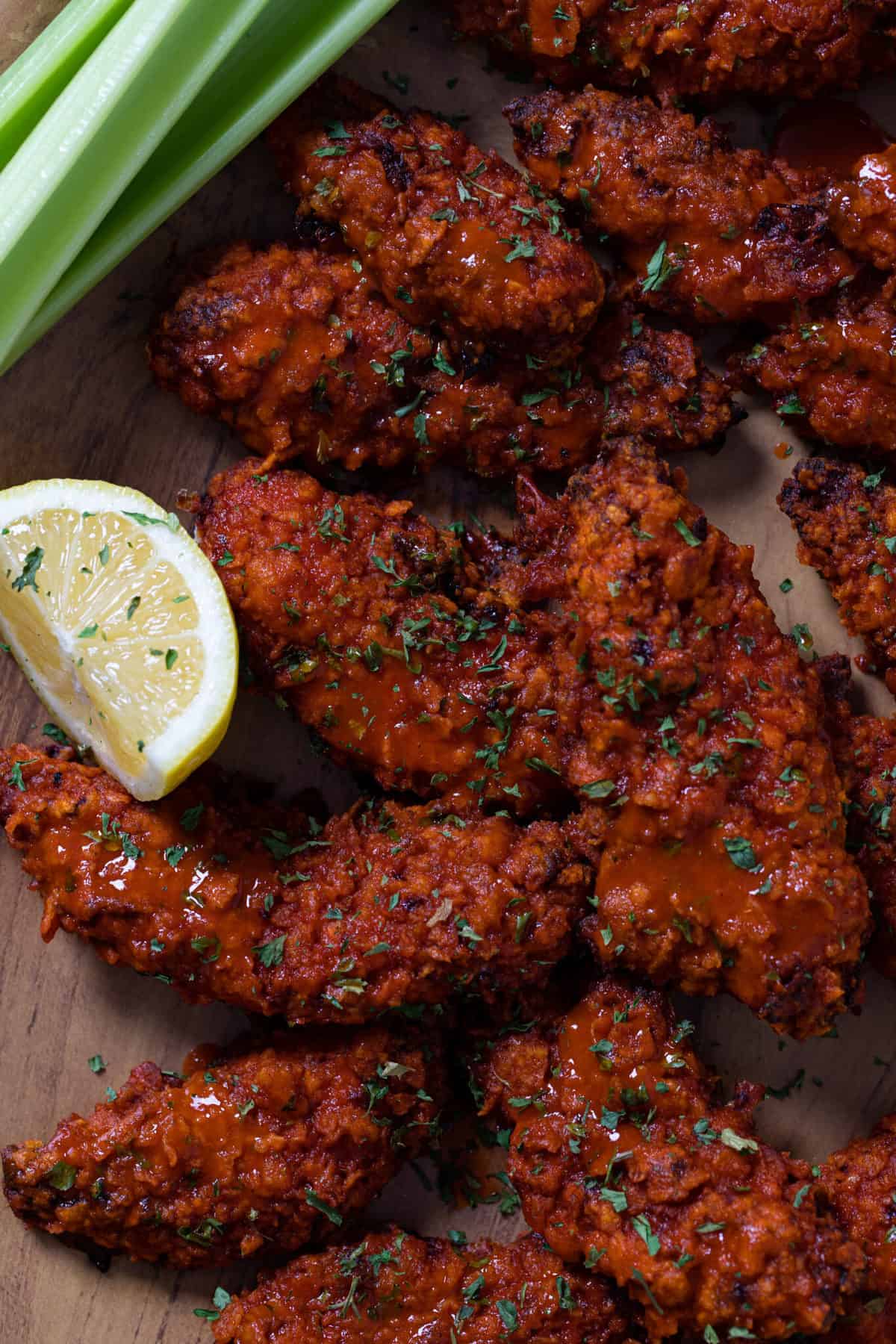 Crispy Buffalo Chicken Tenders with a lemon wedges and celery stalks