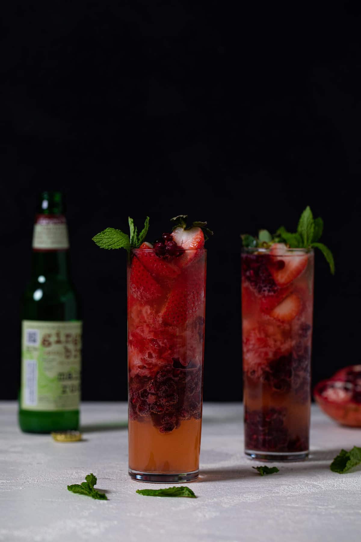 Two Ginger Strawberry Pomegranate Mocktails in tall glasses.