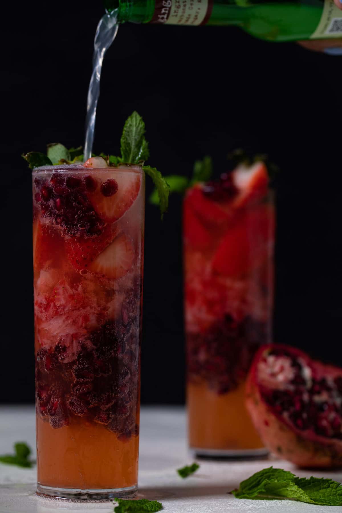 Ginger beer pouring into a Ginger Strawberry Pomegranate Drink.