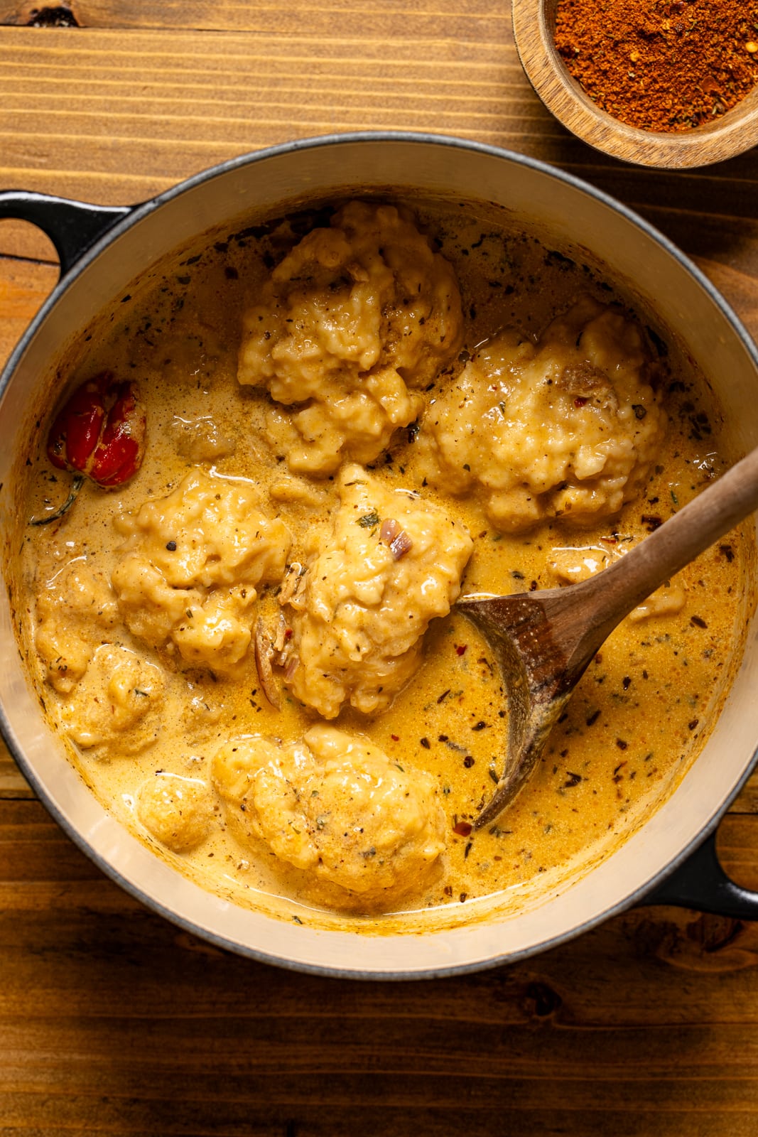 Dutch oven pot with chicken and dumplings with a wooden spoon.