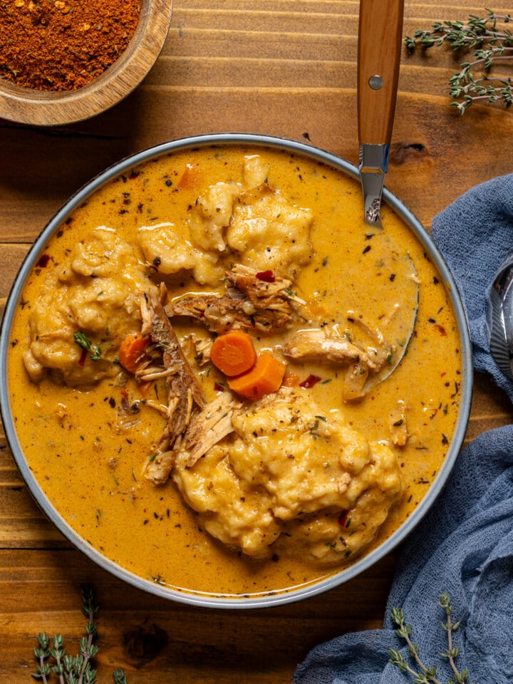 Up close shot of chicken and dumplings on a brown wood table with spoon.