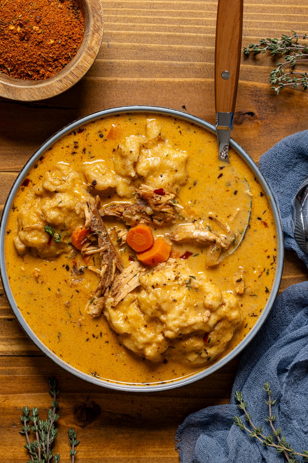 Up close shot of chicken and dumplings on a brown wood table with spoon.