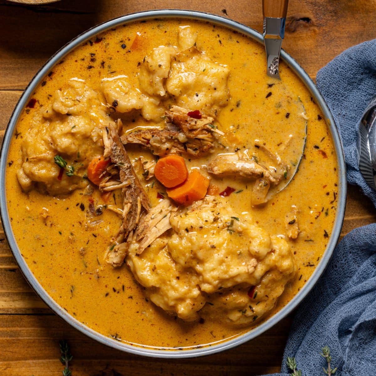 Up close shot of chicken and dumplings on a brown wood table with spoon.